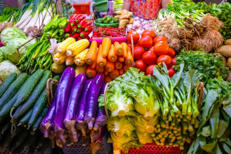 Large stacks of a wide variety of colorful vegetables for sale at market.