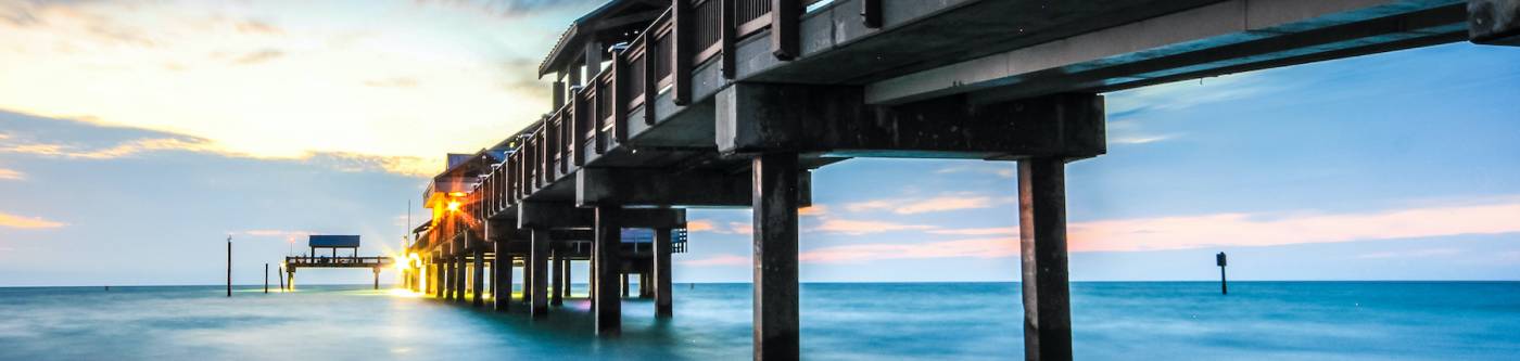 The Clearwater Beach pier from underneath, lit up as sun sets.